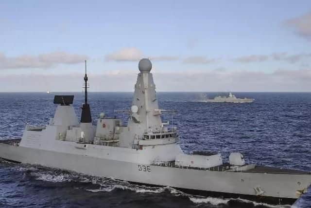 HMS Defender and frigate Admiral Gorshkov in the background as her helicopter lands on deck
