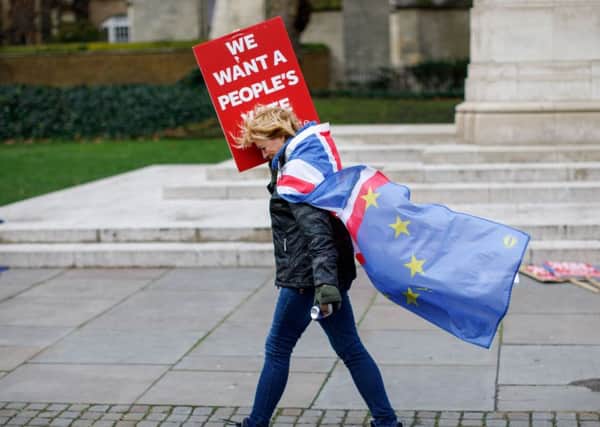 An anti-Brexit protester draped in a composite if the EU and Union flag walks outside the Houses of Parliament in London - (Photo by Tolga Akmen / AFP)