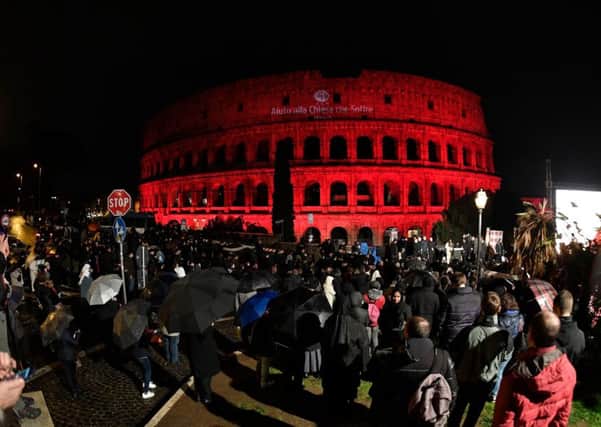 People gather for a ceremony at the Colosseum in Rome, illuminated in red light and reading Aid to the Church that Suffers, drawing attention to the persecution of Christians around the world. Picture: AFP/Getty