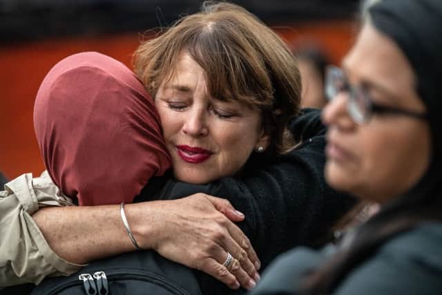 Women hug to comfort each other next to flowers and tributes laid by the wall of the Botanic Gardens on March 17, 2019 in Christchurch, New Zealand. Picture: Carl Court/Getty Images