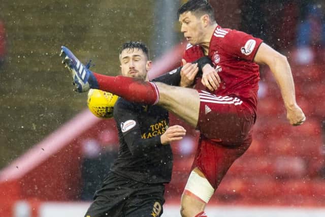 Scott McKenna clears the ball under pressure from Livingston's Ryan Hardie. Picture: SNS Group