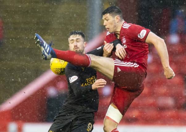 Scott McKenna clears the ball under pressure from Livingston's Ryan Hardie. Picture: SNS Group