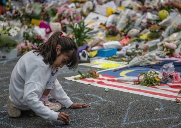 A young girl writes a message in chalk next to flowers near Al Noor mosque in Christchurch (Picture: Carl Court/Getty)