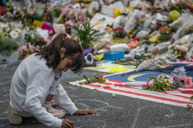 A young girl writes a message in chalk next to flowers near Al Noor mosque in Christchurch (Picture: Carl Court/Getty)