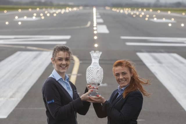 Glasgow Airport employees Sarah Hopkins (L) and Chantelle Docherty with the Solheim Cup trophy on the runway at Glasgow Airport.