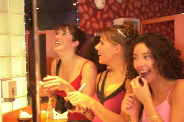 Three ladies top up their make-up in the toilets of the Eros nighclub.