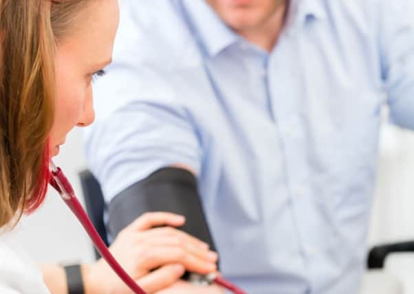 Young female doctor measuring blood pressure of patient in surgery consultation hour.