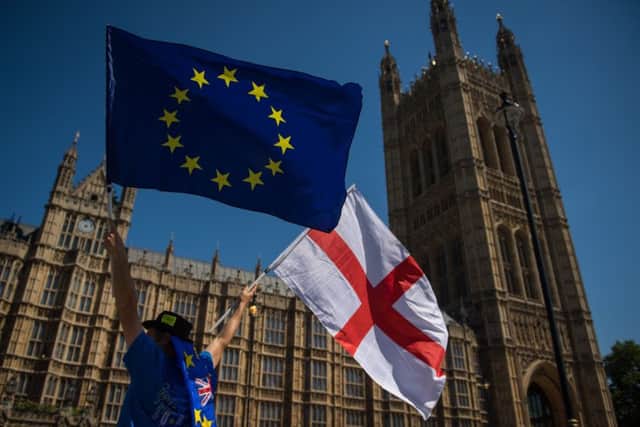 An anti-Brexit demonstrator holds European Union and England flags outside the Houses of Parliament. Picture: PA