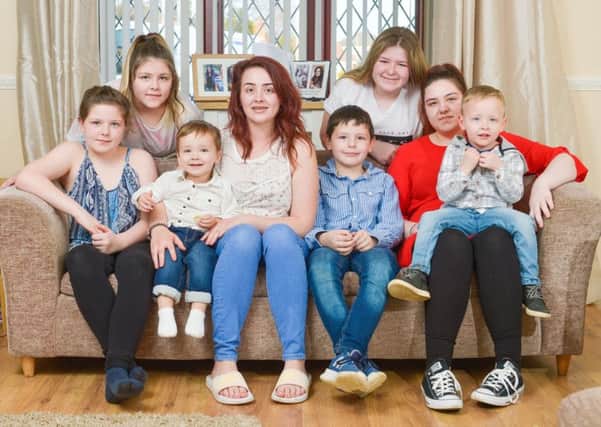 Shannon Ellis, 23 (centre), who has adopted the role of mother to her five younger siblings as well as her own two sons, after their mum passed away, pictured at home in Hartlepool, Teesside. From left (siblings unless specified): Keevie (10), Bracken (13), partner Kieren (23), son Rowan (2), Shannon, Neve (15), Blaine (8), Mia (16), son Harrison (3). Picture: SWNS