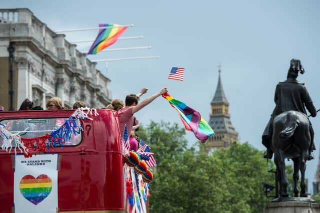 Pride marchers wave American and rainbow flags from the top of a double decker bus with Parliament behind as the LGBT community celebrates Pride in London on June 25, 2016 in London, England. (Photo by Chris J Ratcliffe/Getty Images)