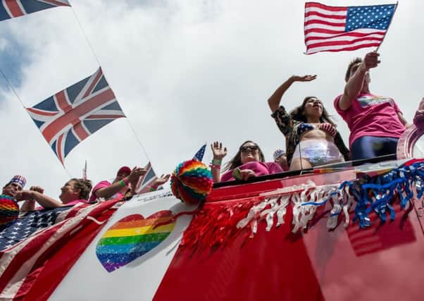 Pride marchers wave American and rainbow flags from the top of a double decker bus as the LGBT community celebrates Pride in London on June 25, 2016 in London, England.  (Photo by Chris J Ratcliffe/Getty Images)
