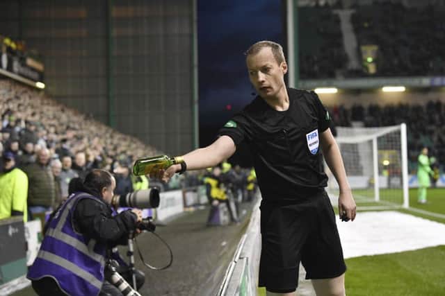 Referee Willie Collum removes a glass bottle from the pitch after it was thrown at Celtic's Scott Sinclair. Picture: SNS Group