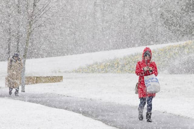 Commuters make their way through April snow showers today in Livingston, West Lothian