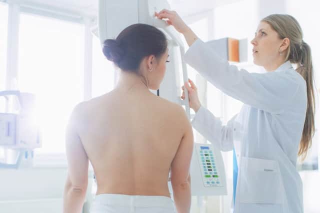 A doctor adjusts a mammogram machine for a female patient