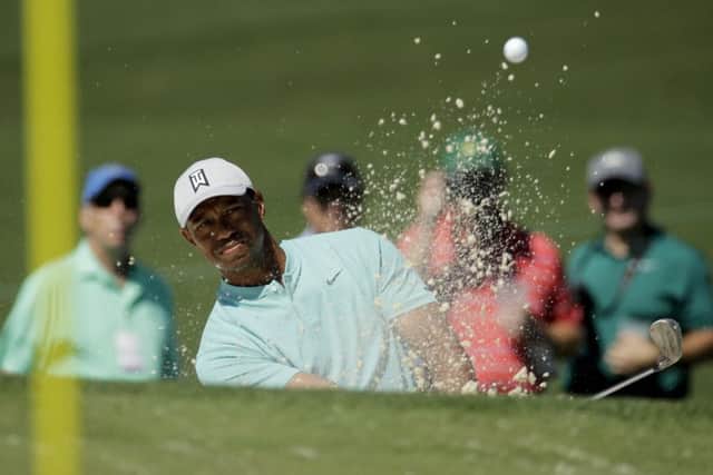 Tiger Woods hits out of the bunker on the second hole during practice. Picture: Charlie Riedel/AP