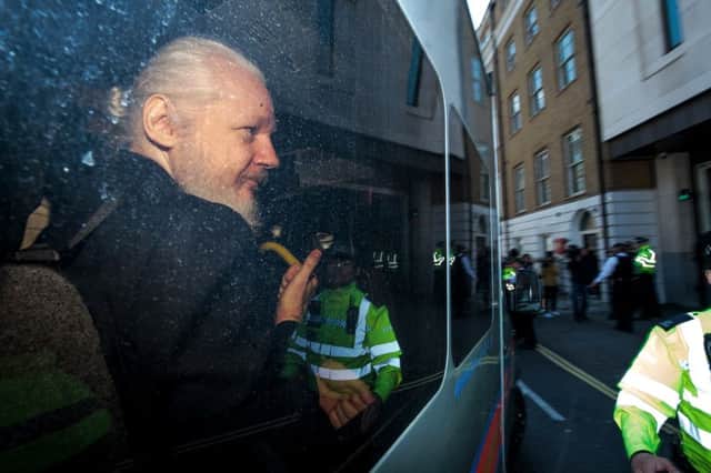 Julian Assange gestures to the media from a police vehicle on his arrival at Westminster Magistrates court. (Photo by Jack Taylor/Getty Images)