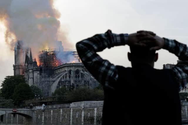 A man watches the landmark Notre-Dame Cathedral burn, engulfed in flames, in central Paris on April 15, 2019. (Photo by Geoffroy VAN DER HASSELT / AFP)