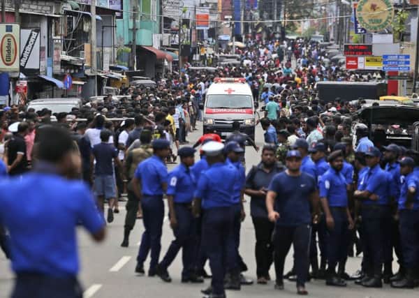 Sri Lankan police officers clear the road as an ambulance drives through carrying injured of Church blasts in Colombo, Sri Lanka. (AP Photo/Eranga Jayawardena)