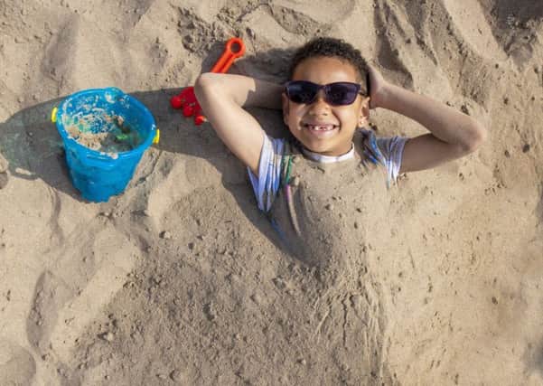 Seven-year-old Curtis Koffi is buried in sand on Broughty Ferry beach, near Dundee. Scotland has enjoyed its hottest Easter Sunday on record