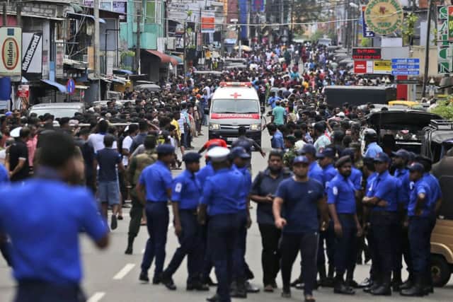 Sri Lankan police officers clear the road as an ambulance drives through carrying injured of Church blasts in Colombo. Picture: AP/Eranga Jayawardena)