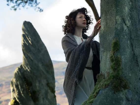 Claire Randall Fraser, played by Caitriona Balfe, travels through hundreds of years in time after touching fictional standing stones at Craigh na Dun in the first season of Outlander.
