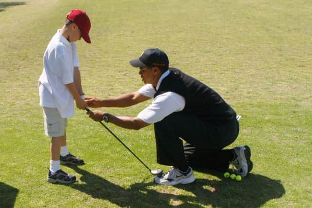 Tiger Woods teaches an eight-year-old budding golfer at his clinic. Now, following his victory in the Masters, junior sessions at clubs around the world are expected to experience a surge in youngsters taking up the sport. Picture: Getty.