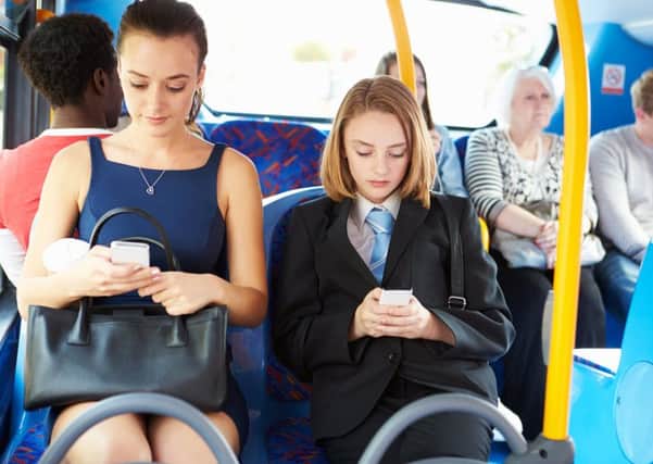 Young passengers sitting on bus sending text messages on mobile phones