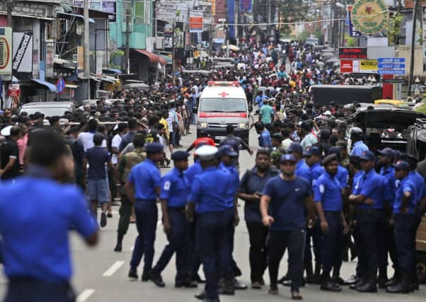 Sri Lankan police officers clear the road as an ambulance drives through carrying injured of Church blasts in Colombo. Picture: AP/Eranga Jayawardena)