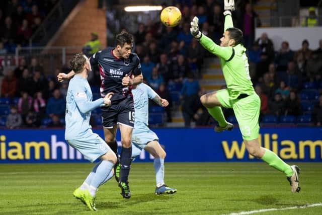 Brian Graham heads past Queen of the South keeper Deniz Mehmet to complete Ross Countys 4-0 victory. Picture: SNS.
