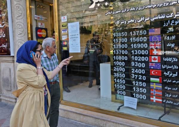 People walk past a currency exchange in Tehran as the rial crashes on international markets amid US sanctions (Picture: Atta Kenare/AFP/Getty Images)