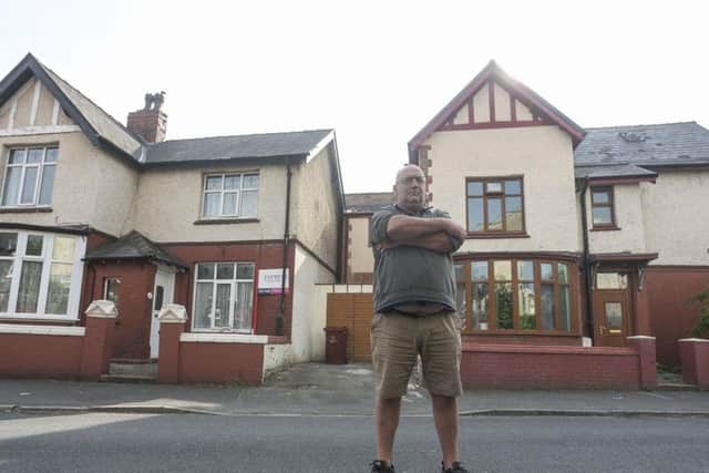 Neal Robinson in front of his house (left) with his neighbour's house (right) and the contentious extension in between the two.