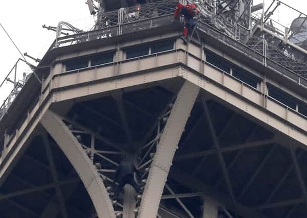A rescue worker, top in red, climbs the Eiffel Tower while a climber is seen below him between two iron columns. Picture: AP Photo/Michel Euler