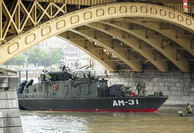 The Dunaujvaros military ship of the Hungarian Army's demolition expert warship regiment at Margaret Bridge during the search operation on the River Danube in Budapest, Hungary, (Balazs Mohai/MTI via AP)