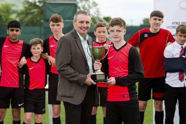 Former Celtic skipper Tom Boyd presents Drumsagards Ross Mullen with the Lisbon Lions Trophy following their 4-0 victory over Stonelaw High School in the final of the tournament which was staged at the Lennoxtown training ground yesterday. Picture: SNS.