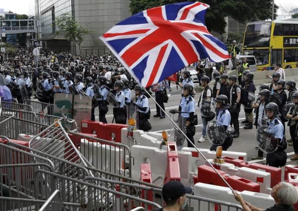 A man waves a British flag as policemen in anti-riot gear stand guard against the protesters in Hong Kong. Picture: AP