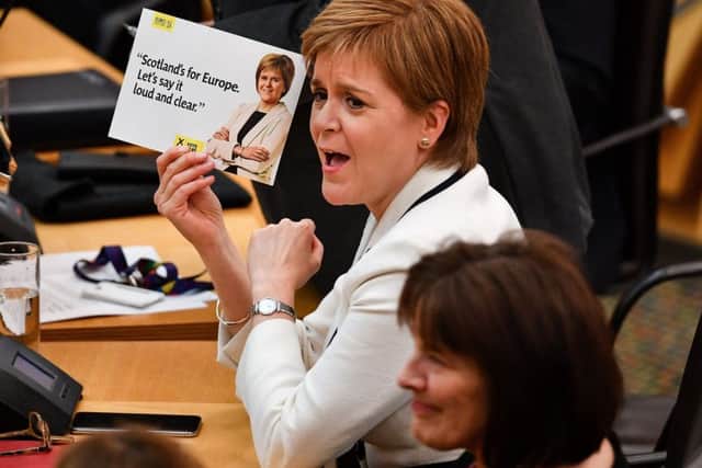 First Minister Nicola Sturgeon holds up a leaflet as Constitutional Relations Secretary Michael Russell addresses MSPs at the Scottish Parliament. Picture: Jeff J Mitchell/Getty Images