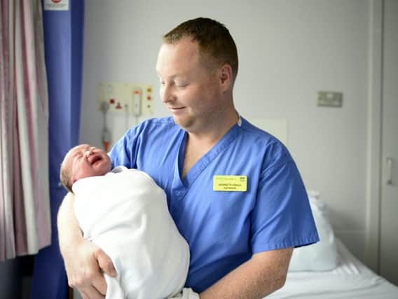 Kenny Gibson with a baby boy he helped deliver. Picture: SWNS