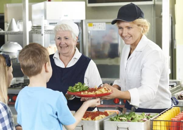 Pupils in a school cafeteria being served lunch