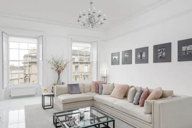 The living room has period features such as a feature fireplace, large shuttered windows and ceiling cornicing.