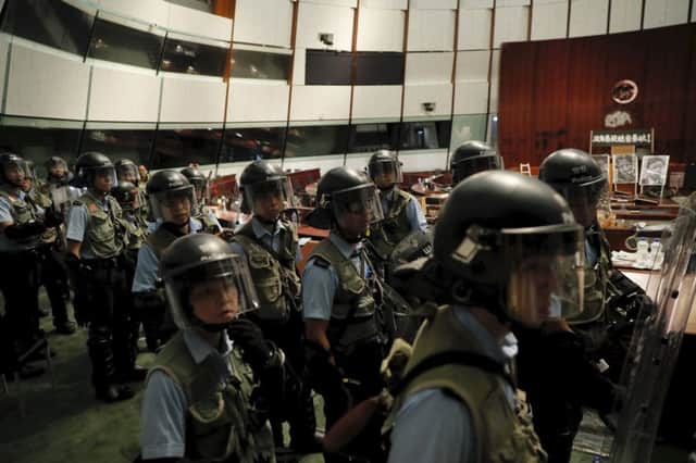 Police in anti-riot gear clear the Legislative Council building, top and above left, after protesters, above, had stormed the complex. Picture: AP