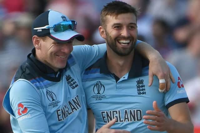 England's Mark Wood, right, celebrates with captain Eoin Morgan after taking the wicket of New Zealand's Mitchell Santner. Picture: Paul Ellis/AFP/Getty