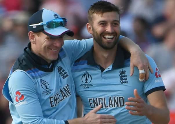 England's Mark Wood, right, celebrates with captain Eoin Morgan after taking the wicket of New Zealand's Mitchell Santner. Picture: Paul Ellis/AFP/Getty