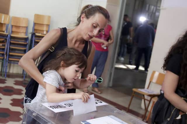 A woman holding her child casts her vote at a polling station during general elections on July 7, 2019 in Athens, Greece. The New Democracy party of Kyriakos Mitsotakis defeated Prime Minister Alexis Tsipras's Syriza party. (Photo by Milos Bicanski/Getty Images)