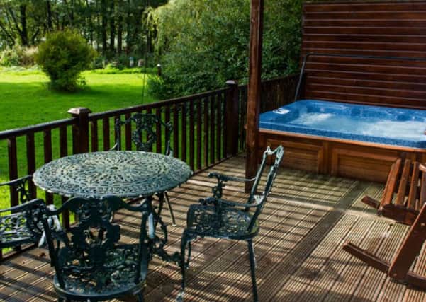 The decking and hot tub outside the french doors of the log cabin