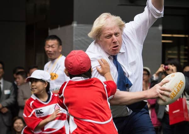 Boris Johnson knocks over a schoolboy while playing rugby in Japan (Picture: Stefan Rousseau/PA Wire