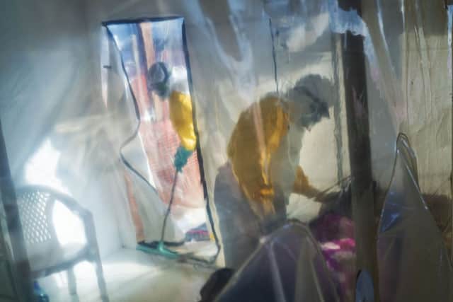 Health workers wearing protective suits tend to to an Ebola victim kept in an isolation cube in Beni, Congo DRC. (AP Photo/Jerome Delay)