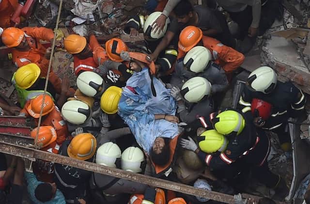Indian National Disaster Response Force and Indian fire brigade personnel rescue a survivor after a building collapsed in Mumbai on July 16, 2019. - Two people were killed and more than 40 trapped under the rubble after a building collapsed as heavy monsoon rains lashed India's financial capital Mumbai on July 16, officials said, the second such tragedy in two weeks. (Photo by PUNIT PARANJPE / AFP)PUNIT PARANJPE/AFP/Getty Images