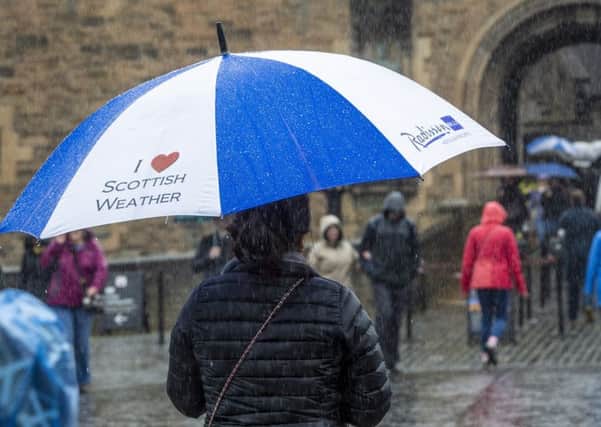 Tourists at Edinburgh Castle battle heavy rain.