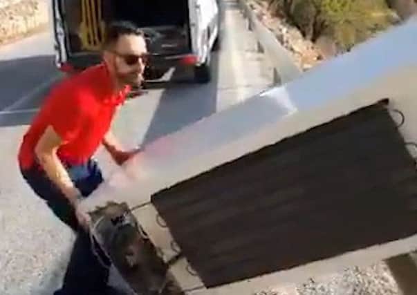 A video grab from the moment a man throws a fridge over a cliff in southern Almeria, Spain  only to be later ordered to bring it back up (Picture: Picture: AUGC Guardia Civil/SWNS)