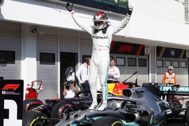 Lewis Hamilton leaps on to the bonnet of his car in celebration following his victory in Hungary. Picture: AP.
